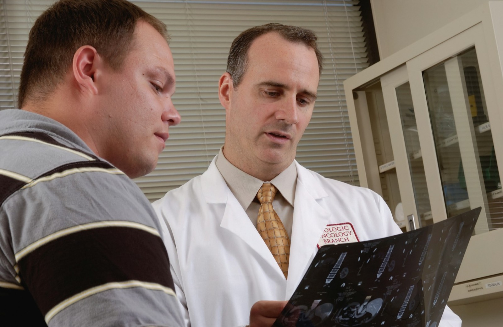 A doctor talking through a printed report with an older man in a consulting room
