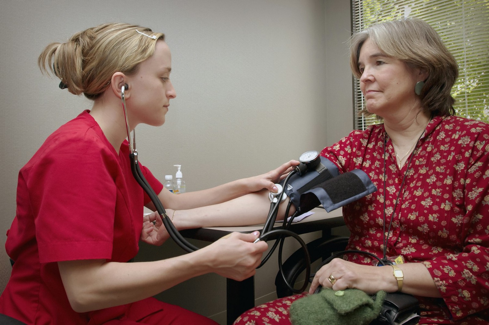 A nurse taking an older woman's blood pressure at a clinic