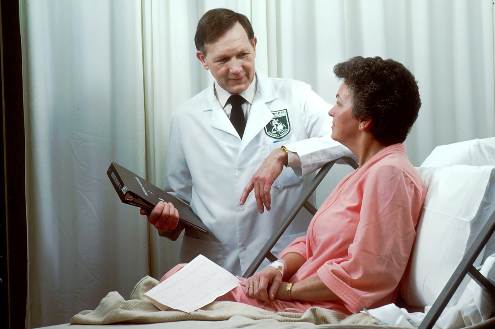 A doctor talking with a woman sitting up in a hospital bed