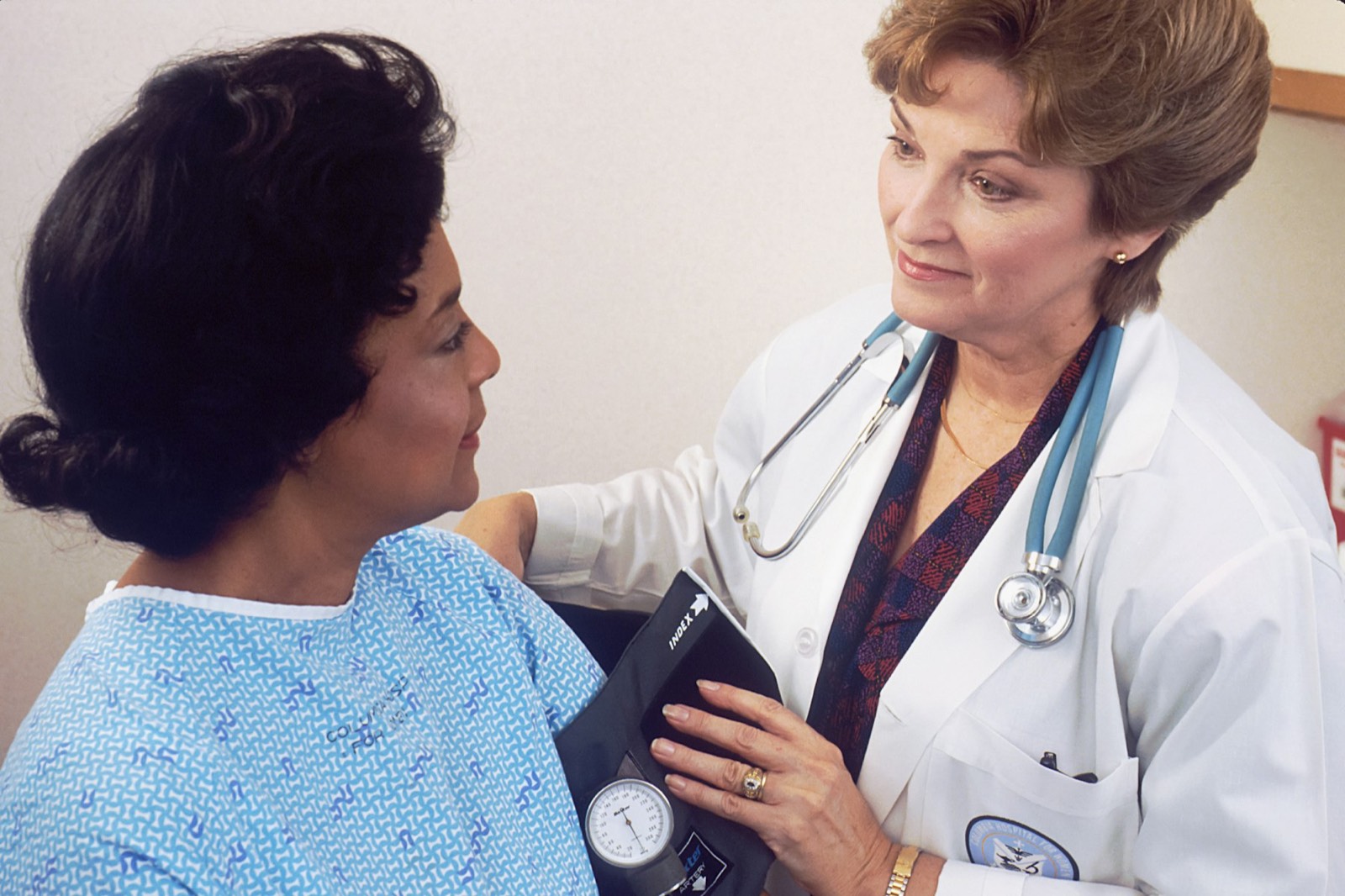A doctor talking with a woman in a hospital gown during a check-up
