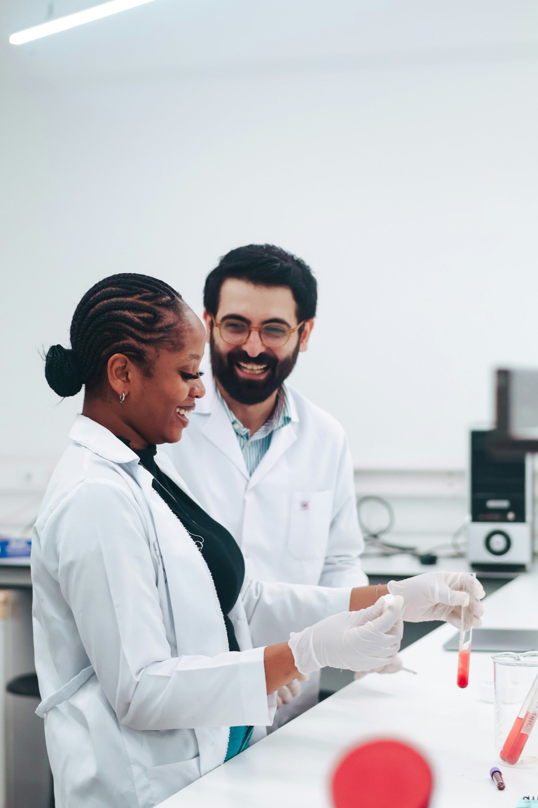 Two researchers in lab coats smiling over a sample