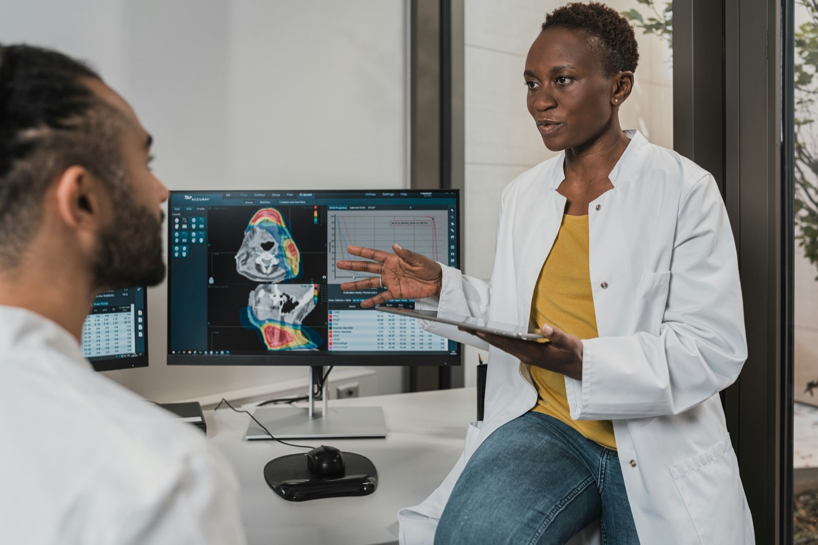 A doctor showing a colleague a scan on a large screen